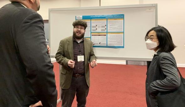 Three people talk in front of a whiteboard.