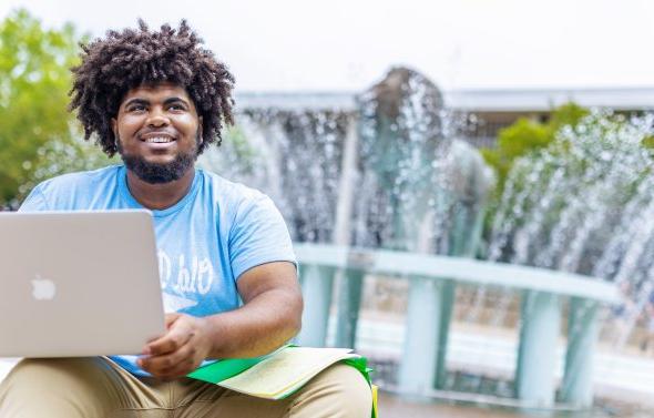 student sitting at the base of the lion fountain smiling